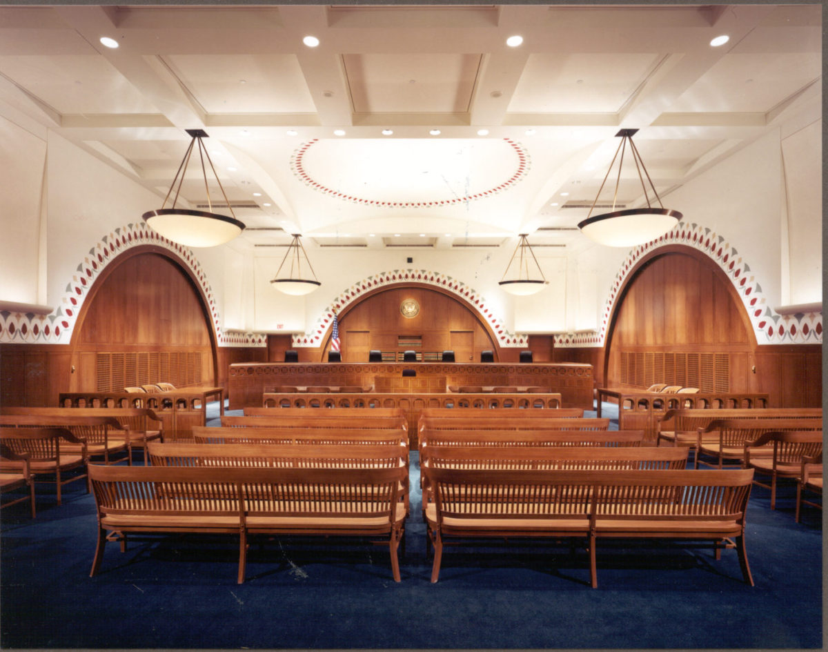 Courtroom interior with wooden benches and arches.